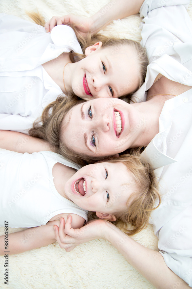Portrait of mom and her daughters smiling on the bed topview Portrait of mom and her daughters smiling on the bed topview