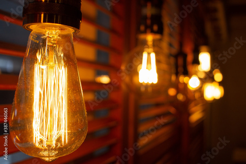 Golden shining antique Edison style bulbs in the dark. Lighting decor concept. Vintage light bulb. Blur background of retro lights © axivan.com