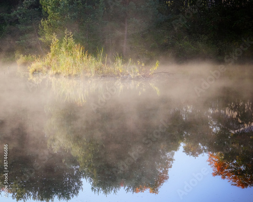 Early morning mist burning off a pond with reflections in the water