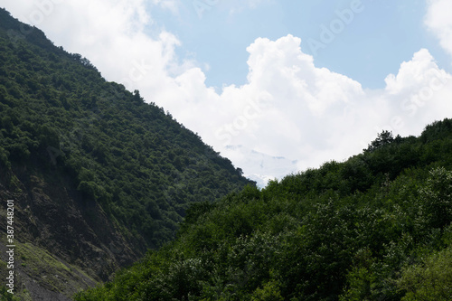 View of the mountains of the North Caucasus. Karmadon gorge. Mount Kazbek in the clouds. Mountains in the clouds in summer