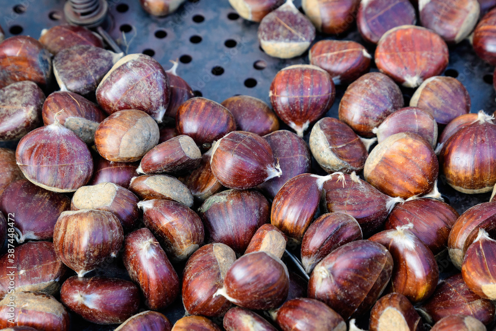 Fall and winter rustic dessert sweet roasted chestnuts in a large metallic bowl, available for sale at a street food market festival, seasonal food photograph with selective focus. Fall and winter rustic dessert sweet roasted chestnuts in a large metallic bowl, available for sale at a street food market festival, seasonal food photograph with selective focus.