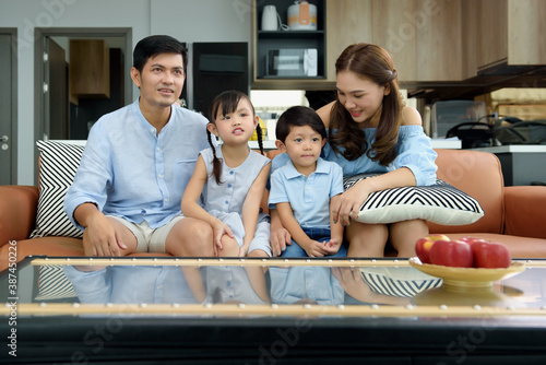 Happy family sitting on sofa in the living room at homes while looking television show and entertainment together. Parents take care of their children and Create activities together in the family. © kokliang1981