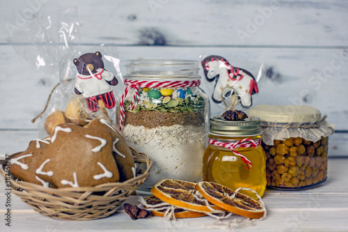 Homemade Christmas Food Gifts.Homemade cookies nuts, gingerbread, a jar of honey, dried oranges, a mixture for baking cookies in a jar on a wooden background. The concept of cozy, soulful DIY gifts
