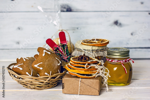Homemade Christmas Food Gifts.Homemade cookies nuts, gingerbread, a jar of honey, dried oranges, a mixture for baking cookies in a jar on a wooden background. The concept of cozy, soulful DIY gifts