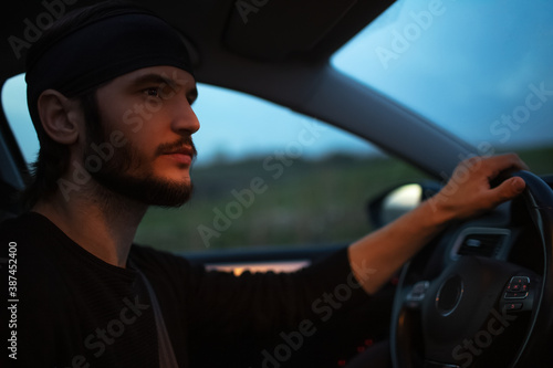 Night portrait of young hipster man driving the car. © Lalandrew