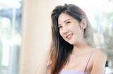 Portrait of young Asian woman smiling friendly wearing blank vest looking away while sitting at cafe with copy space.Woman lifestyle, Happiness, Holiday concept.