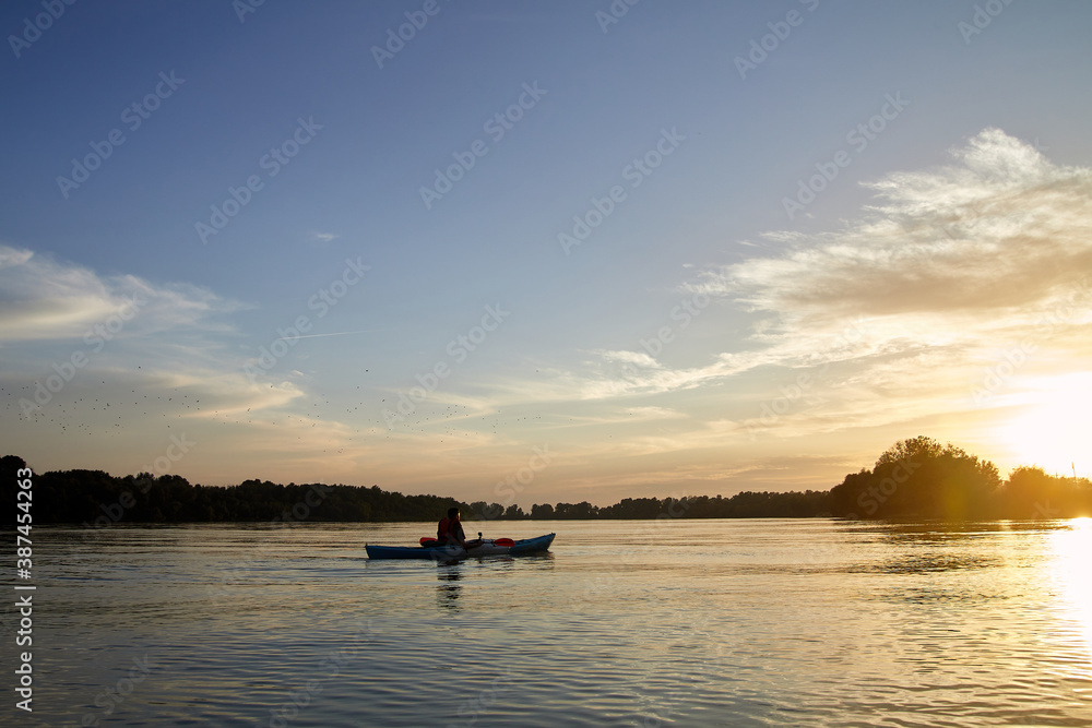 Sillouette of man kayaking on the Danube river at sunset