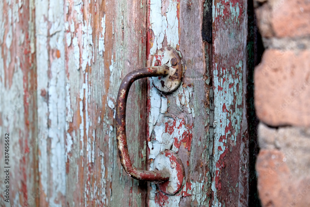 Rusty iron handle on a old wooden door with peeled blue paint abstract background.
