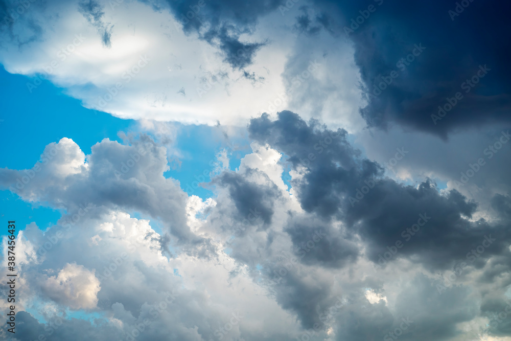 Fototapeta premium Bright blue sky with gray clouds. Sun rays. Horizontal photo.
