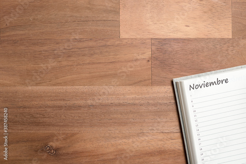 Blank page of a daily planner in Spanish for the month of November, wooden desk