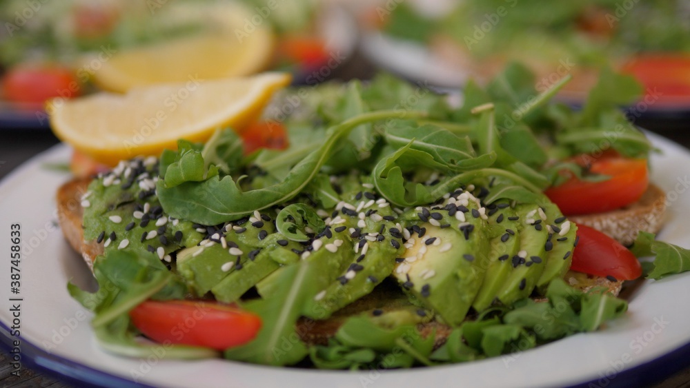 Close up of three servings of avocado toast with green salad, veggies, seeds. Healthy vegan meal concept. Close up of three servings of avocado toast with green salad, veggies, seeds. Healthy vegan meal concept.