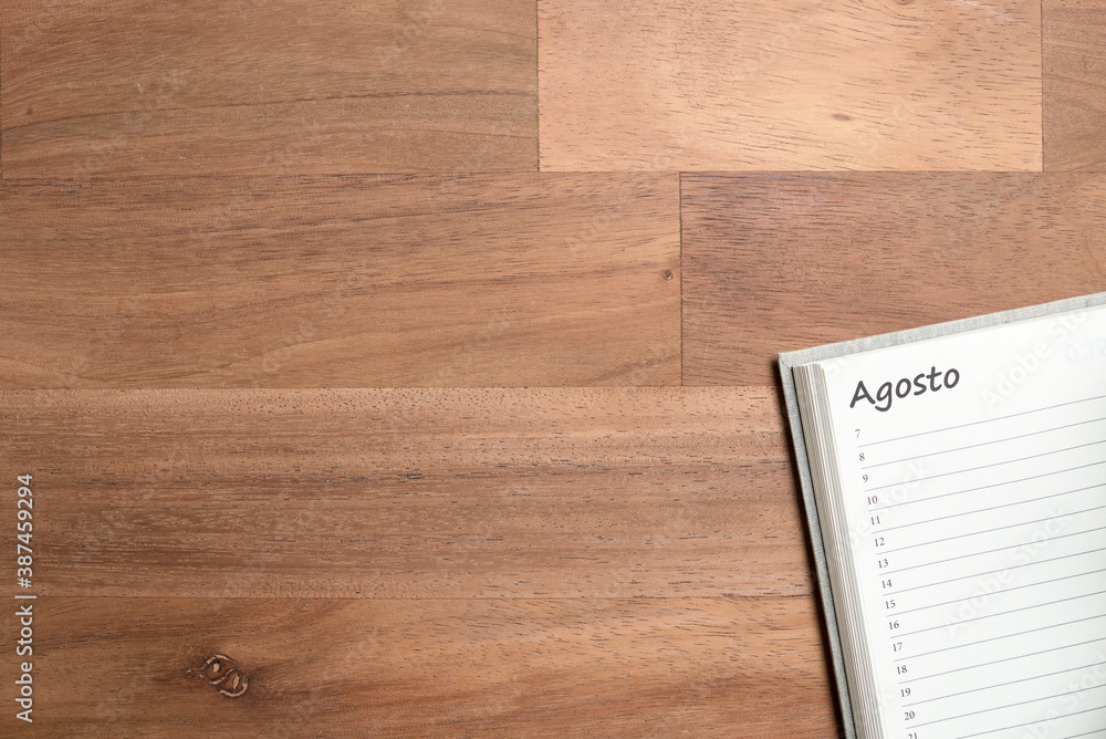 Blank page of a daily planner in Spanish for the month of August and wooden desk Blank page of a daily planner in Spanish for the month of August and wooden desk