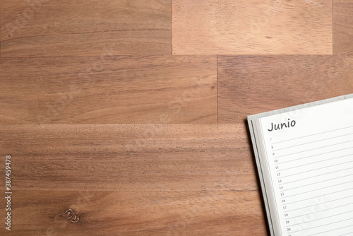 Blank page of a daily planner in Spanish for the month of June, on a wooden desk