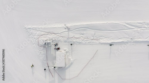 Cableway for transportation skiers and snowboarders. Drone top view people start going up riding on ski and snowboard on snow mountain in winter resort. Ski lift elevator on rope way in snow slope