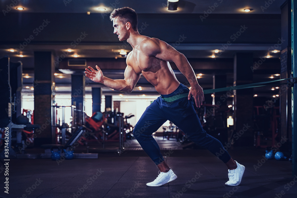 Fototapeta premium Young athlete doing exercises with a resistance band.