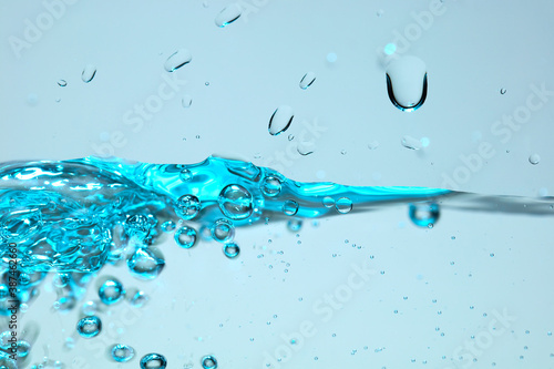 Nahaufnahme einer blauen Wasseroberfläche mit Wassertropfen und Luftblasen.