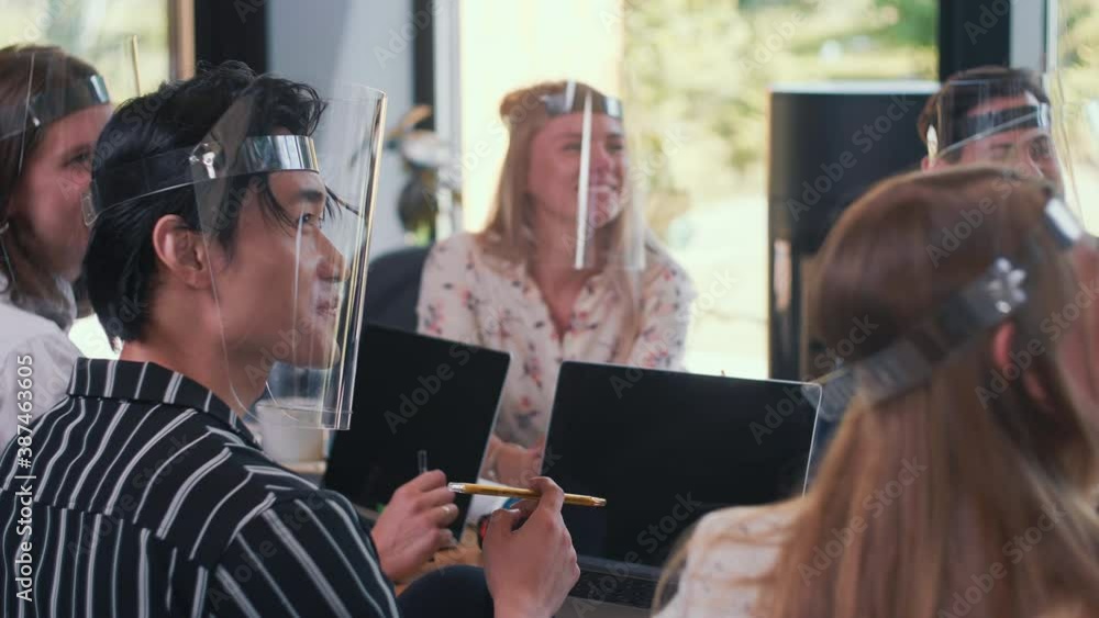 Teamwork after COVID-19. Happy positive young multiethnic business partners work together wearing plastic face shields. Teamwork after COVID-19. Happy positive young multiethnic business partners work together wearing plastic face shields.