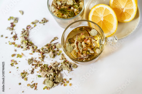 2 cup of medicinal tea from Origanum Dictamnus,  lemon and dried herb spilled on white background, closeup. photo