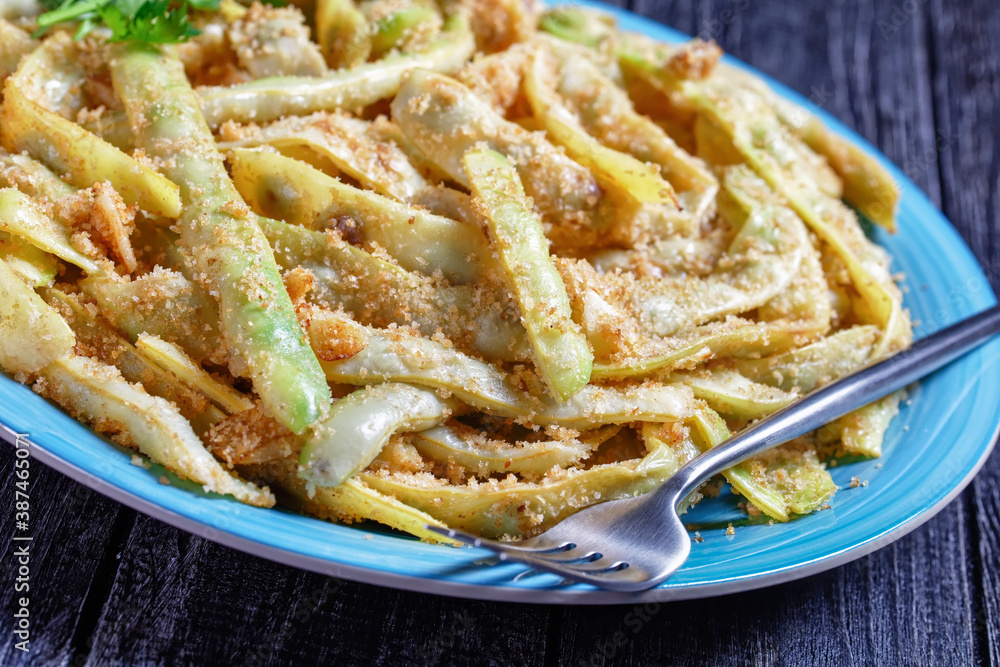 Golden french wax beans on a blue plate, close-up