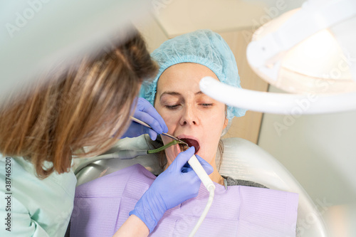 Female dentist doctor treats teeth of a young girl sitting in the chair