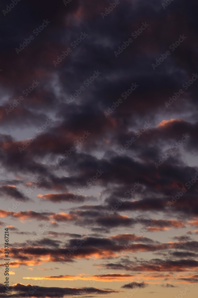 Epic dramatic sunset, sunrise sky with dark violet clouds in orange yellow sunlight	