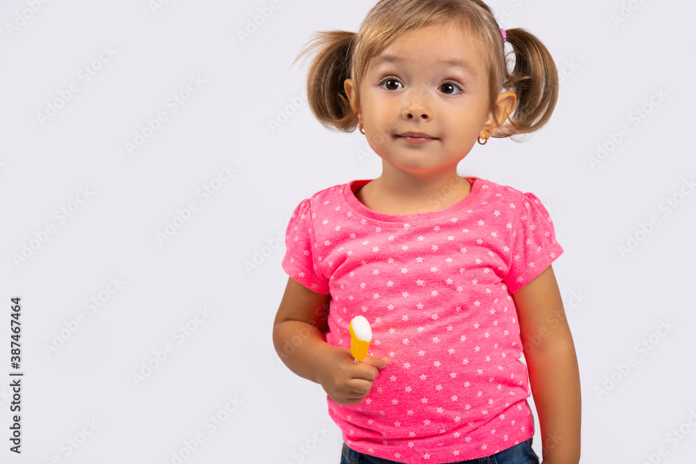 Portrait of a small, cute and beautiful girl with ponytails and lollipop in her hands. Photo on white background with empty side space Portrait of a small, cute and beautiful girl with ponytails and lollipop in her hands. Photo on white background with empty side space