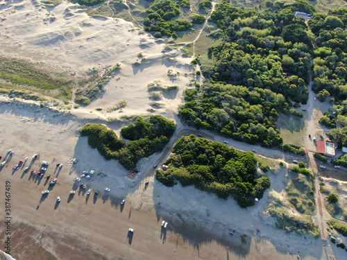 Vista aérea cenital de la playa, con automóviles y personas descansando, durante el atardecer. photo