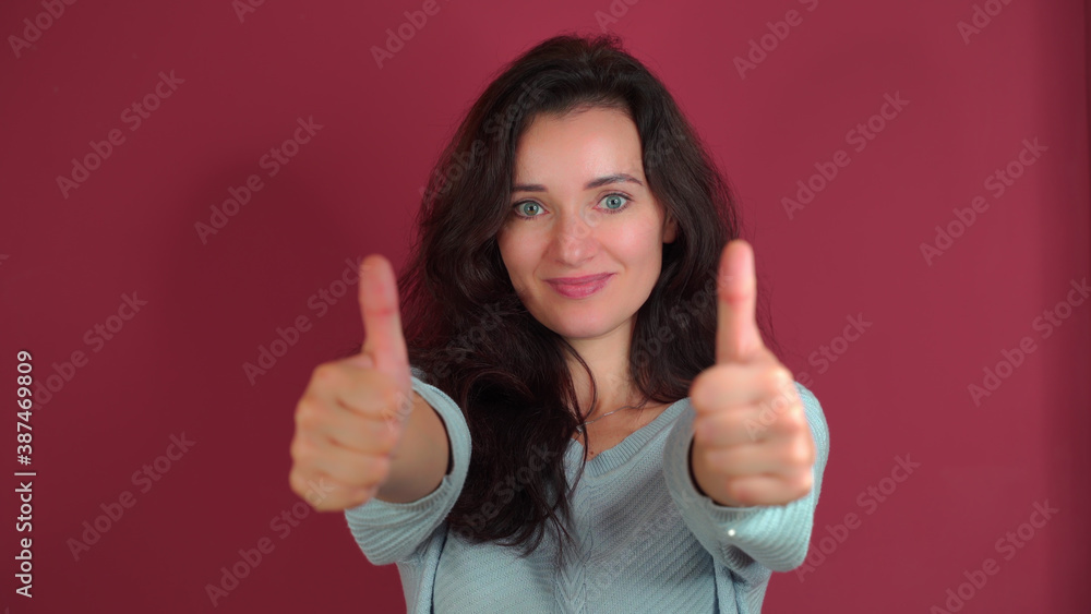 Young beautiful girl shows two thumbs up on a purple background. Young beautiful girl shows two thumbs up on a purple background.