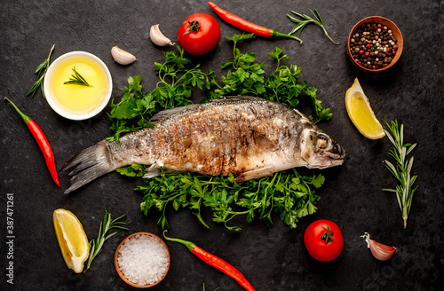 grilled sea bass with spices, herbs, and lemon on a stone background