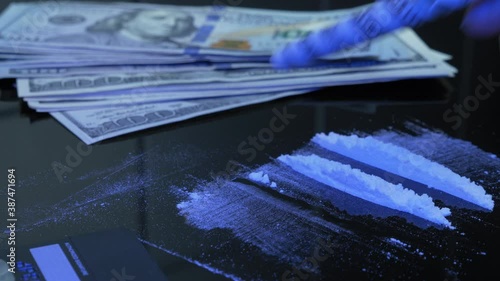 Addict is snorting cocaine or heroin white drug powder off black table with straw of US dollar banknote. Dope fiend is using drugs. Man sniffs line of amphetamines powder through money bill