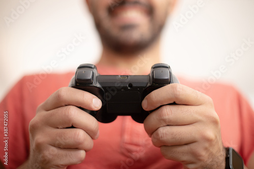 Caucasian player plays video game in his leisure. Happy smiling boy is having fun with his controller. Gaming concept. Close up portrait