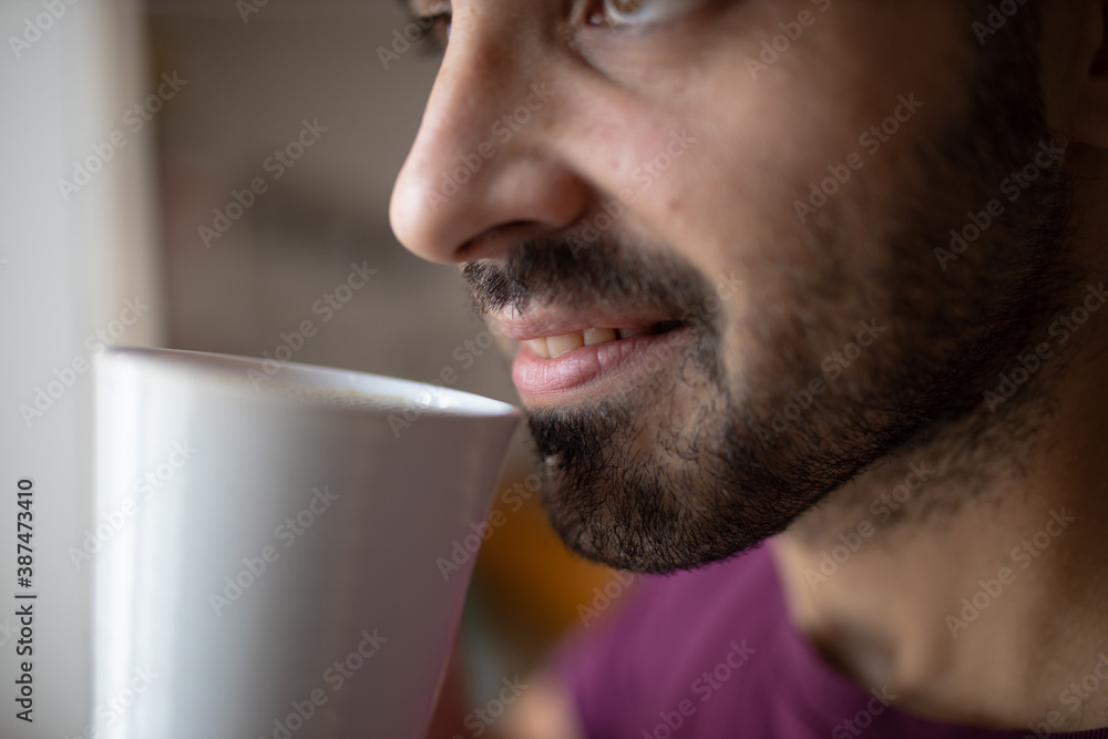 Attractive caucasian man drinks his tea cup in the morning. Breakfast at home, break time with a fresh cup of tea. Close up shot of smiling boy that drinks Attractive caucasian man drinks his tea cup in the morning. Breakfast at home, break time with a fresh cup of tea. Close up shot of smiling boy that drinks
