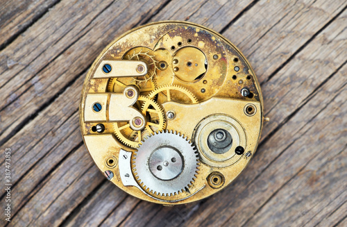 Antique metal pocket watch clockwork with gears on wooden background