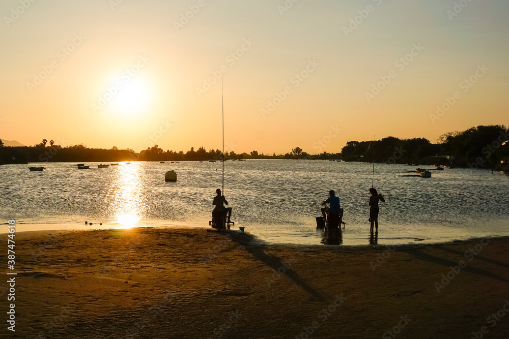 people fishing in the lagoon at sunset