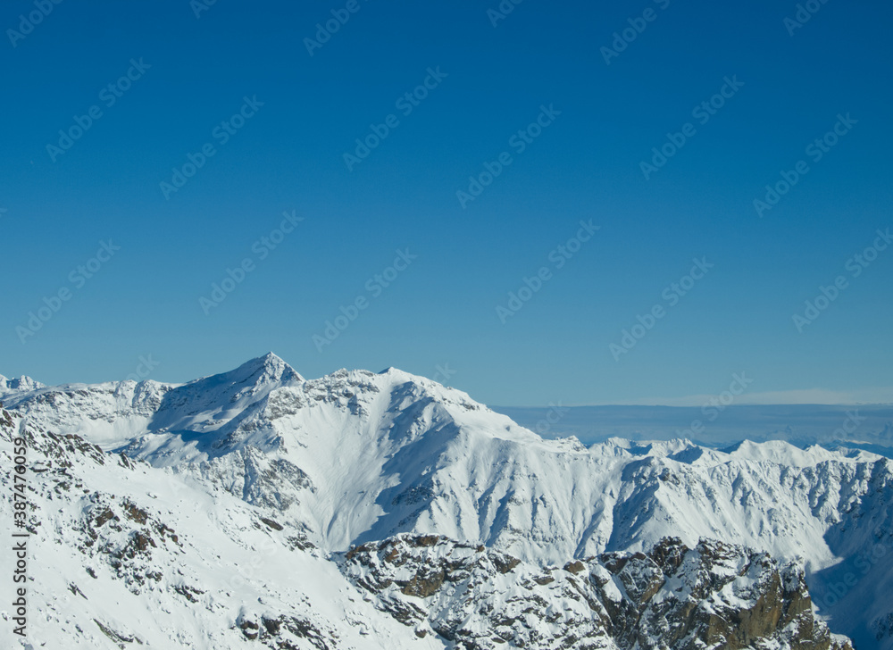 Beautiful winter landscape with snow covered mountains and rocks. Blue sky and fresh snow in the Alps. Beautiful European alpine winter scenery. Natural background with horizon line. Italy, Trentino.