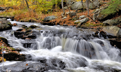 Moss-covered boulders, autumn leaves, and rapids along swift flowing Willard Brook in Willard Brook State Park, Massachusetts.