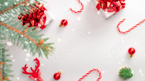 Surprise box. White gifts with scarlet bow, red balls and winter tree in xmas decoration on white background for greeting card. Flat lay, top view, copy space.