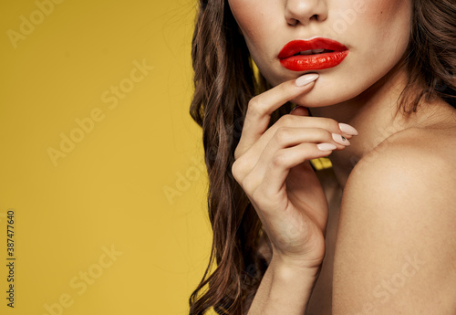 Portrait of a woman with bright makeup on a yellow background bared shoulders cropped view