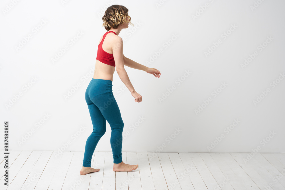 woman in leggings is engaged in gymnastics in a light room slim figure fitness sport - obrazy, fototapety, plakaty 