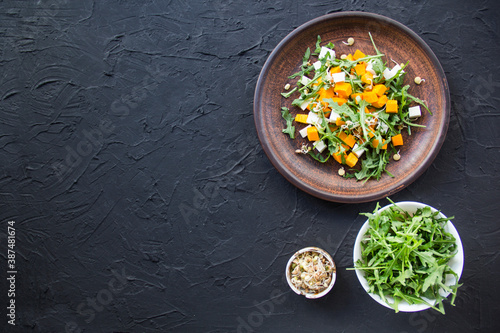 Delicious healthy pumpkin salad with arugula and cheese. Creative atmospheric decoration