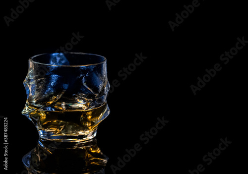 Фотография barman pouring whiskey in front of whiskey glass and bottles on black table with