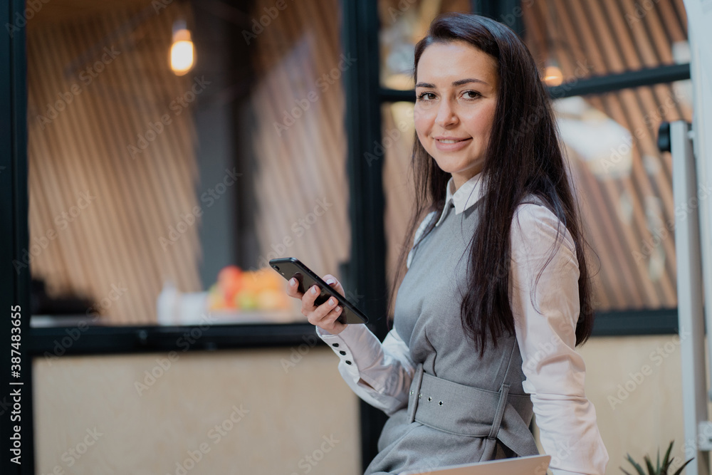 Bank employee General Manager confident woman, holding a phone. European-looking brunette. career in the field of money securities investments, favorite work.