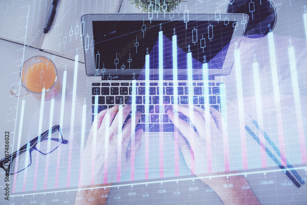 Double exposure of man's hands typing over laptop keyboard and forex chart hologram drawing. Top view. Financial markets concept.