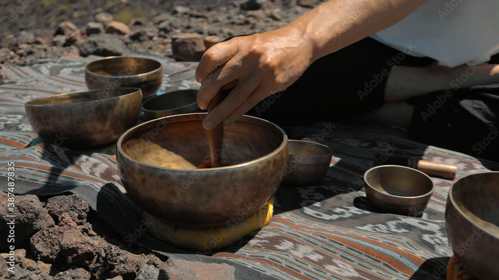Asian guy playing Tibedt singing copper cups on a viewing mountain Asian guy playing Tibedt singing copper cups on a viewing mountain