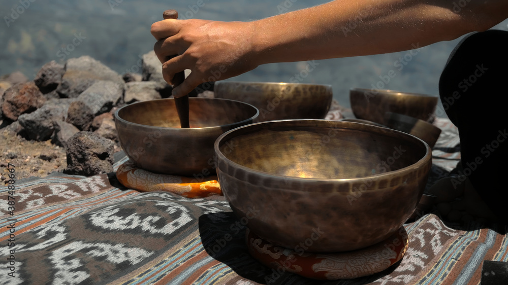 Asian guy playing Tibedt singing copper cups on a viewing mountain Asian guy playing Tibedt singing copper cups on a viewing mountain