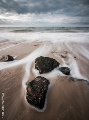 water flowing smoothly around stones at a beach at the North Sea, Germany (long exposure) photo