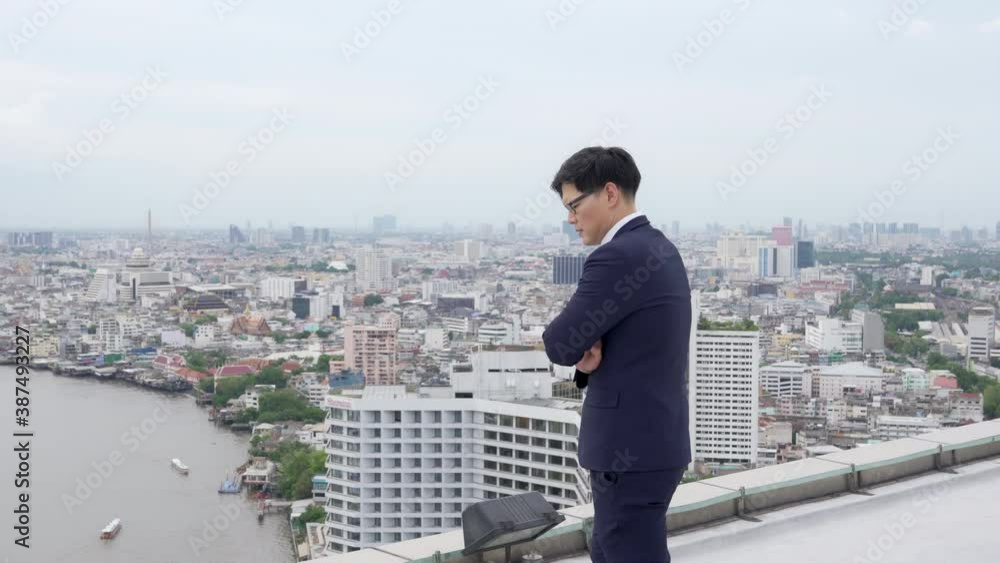 4K Stressed Asian businessman entrepreneur walking around office building rooftop and think of business problem. Serious man employee unsuccessful in work. Unemployed and financial crisis concept 4K Stressed Asian businessman entrepreneur walking around office building rooftop and think of business problem. Serious man employee unsuccessful in work. Unemployed and financial crisis concept