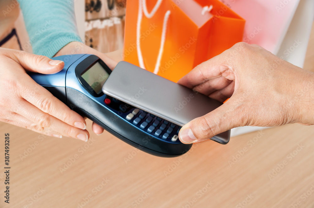 Fototapeta premium Closeup shot of a man paying using NFC technology or dataphone in a clothing store