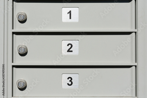 Close up. Locked doors of outdoor apartment mailbox with numbers 1, 2 and 3