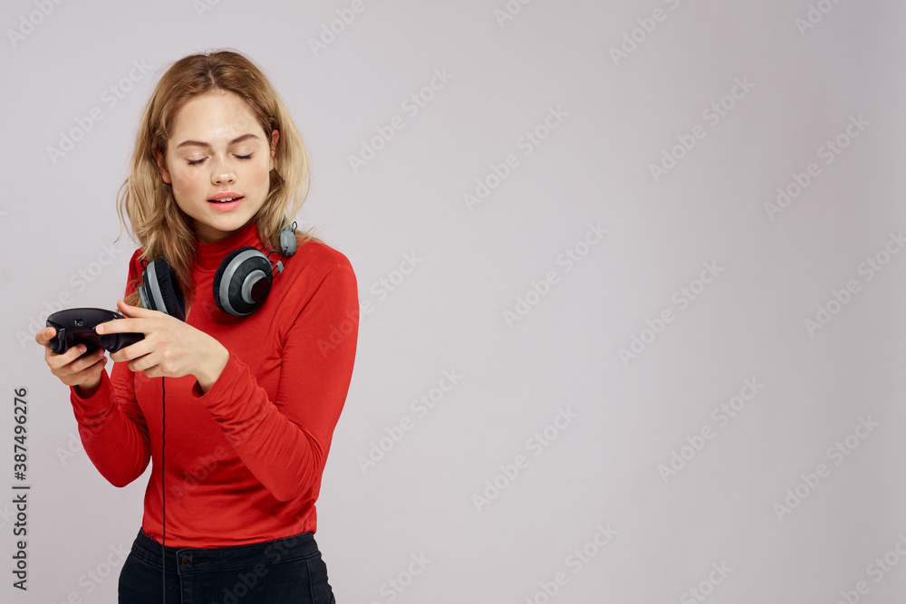 Woman with headphones controller in hands a console game fun leisure red jacket lifestyle light background Woman with headphones controller in hands a console game fun leisure red jacket lifestyle light background